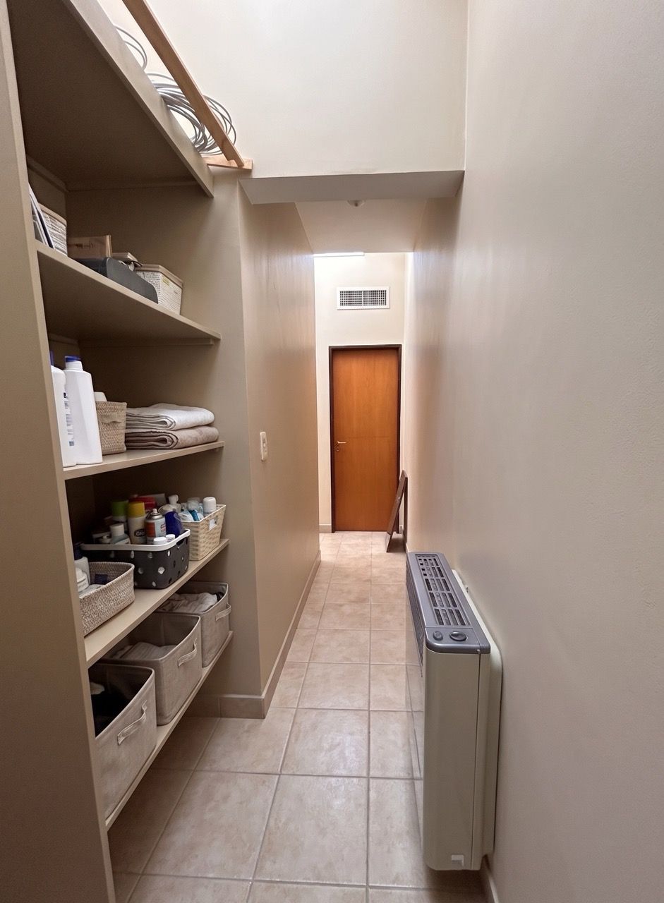 Pasillo con estantes a un lado, un calefactor y una puerta de madera al fondo