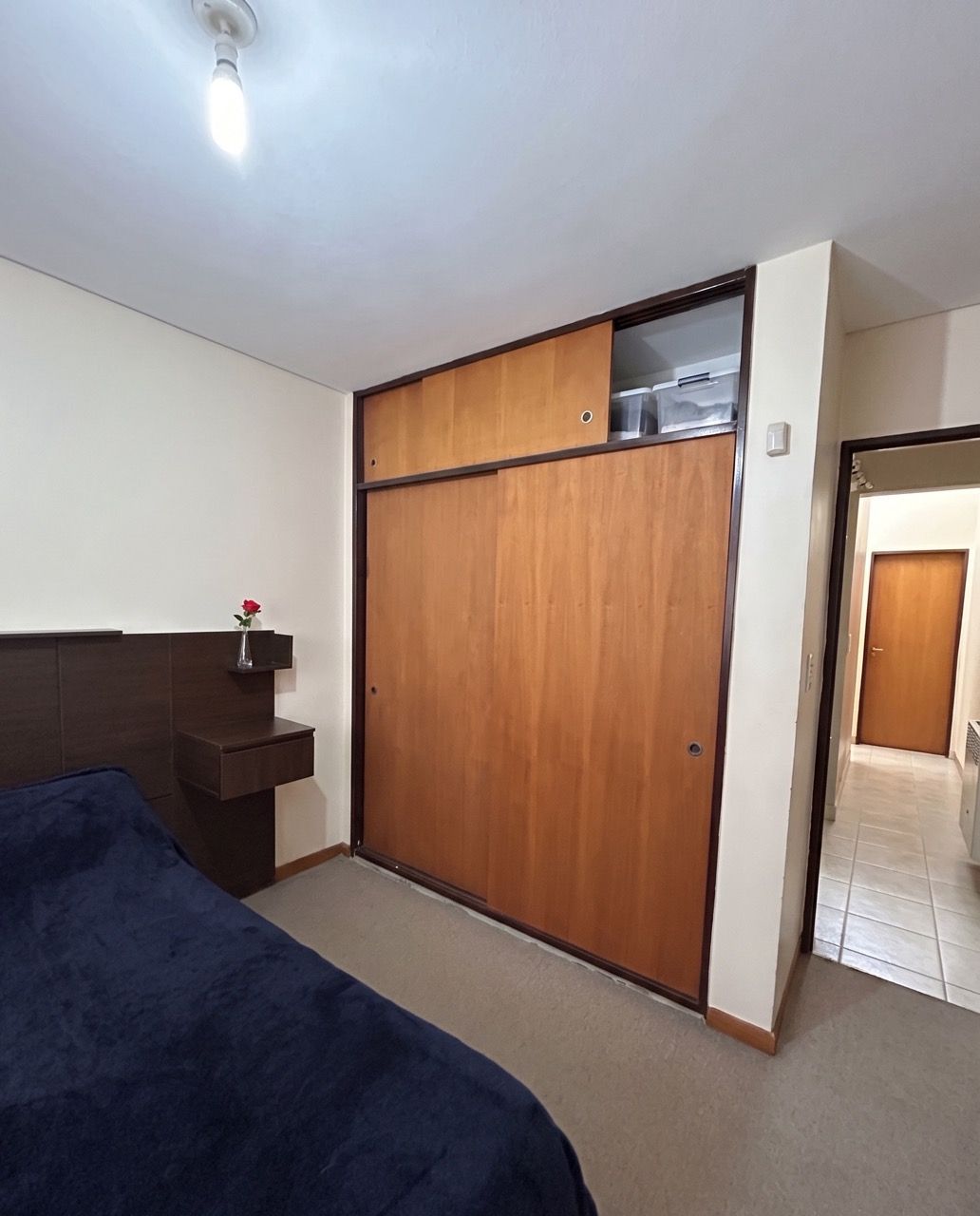Dormitorio visto hacia el placard de madera, con la puerta al pasillo